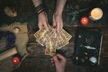 Tarot kartları, sihirli kitap ve servet anlatan bir ahşap masa arka plan üzerinde eller. Gelecekteki okuma kavramı. Kehanet.