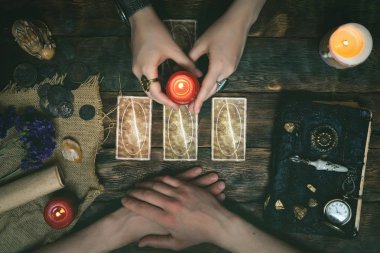 Tarot kartları, sihirli kitap ve servet anlatan bir ahşap masa arka plan üzerinde eller. Gelecekteki okuma kavramı. Kehanet.
