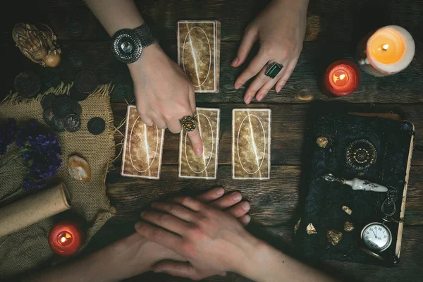 Tarot kartları, sihirli kitap ve servet anlatan bir ahşap masa arka plan üzerinde eller. Gelecekteki okuma kavramı. Kehanet.