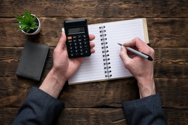 İş adamı bir hesap makinesi üzerinde para sayma ve bir miktar bir defter ile boş bir sayfa yazma. Muhasebeci.