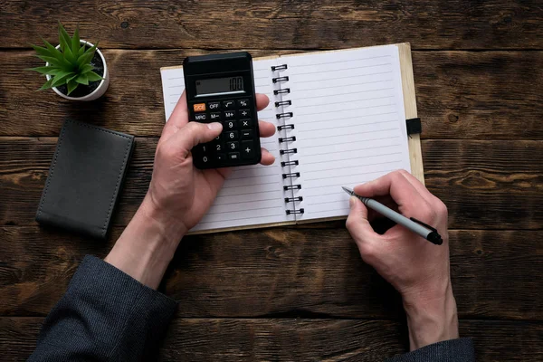 İş adamı bir hesap makinesi üzerinde para sayma ve bir miktar bir defter ile boş bir sayfa yazma. Muhasebeci.