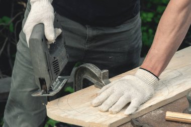 İşçi bir yapboz ile tahta testeresi kesiyor..