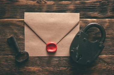 Zarftaki çok gizli belgeler, paslı asma kilit ve tahta bir masanın arka planında duran bir anahtar. Gizli bilgi kavramı.