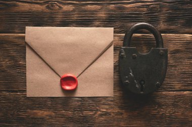 Zarftaki çok gizli belgeler, paslı asma kilit ve tahta bir masanın arka planında duran bir anahtar. Gizli bilgi kavramı.