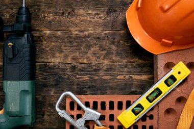 Fotokopi alanı olan bir inşaat konsepti. Sert şapka, tuğla, çekiç matkabı ve kahverengi ahşap işçilikte kabarcık seviyesi.