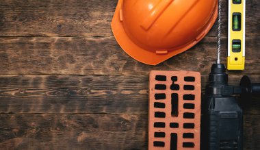 Fotokopi alanı olan bir inşaat konsepti. Sert şapka, tuğla, çekiç matkabı ve kahverengi ahşap işçilikte kabarcık seviyesi.