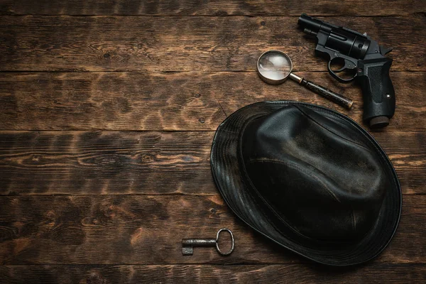 コピースペース付きの探偵やスパイエージェント木製のテーブルフラットレイアウトの背景 黒革の帽子 虫眼鏡と作業台の錆びたキー — ストック写真