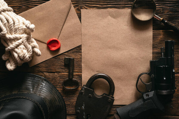 Top secret information mockup, leather hat, weapon, magnifying glass and rope on a wooden table of secret service agent flat lay background.