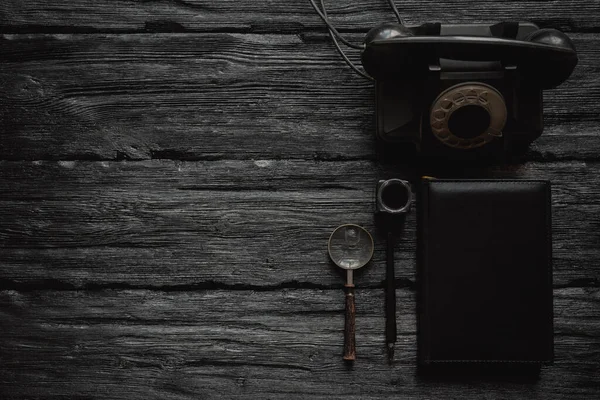 黒の古いロータリー電話 静かなペン 虫眼鏡とコピースペースと黒の木製のテーブルフラットレイアウトの背景に本 お問い合わせ — ストック写真