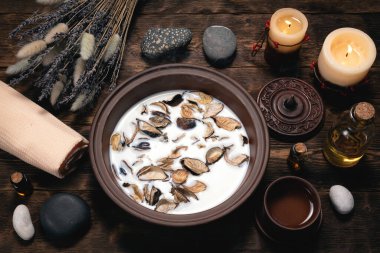 Aromaterapi konsepti geçmişi. Süt, tütsülenmiş bir kâse ve kahverengi ahşap bir masa üzerinde gerekli yağ..