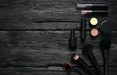 Makyaj fırçaları ve kozmetik düz arka plan ve fotokopi alanı. Siyah ahşap bir masaya aksesuar yap..