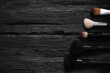 Makyaj fırçaları ve kozmetik düz arka plan ve fotokopi alanı. Siyah ahşap bir masaya aksesuar yap..