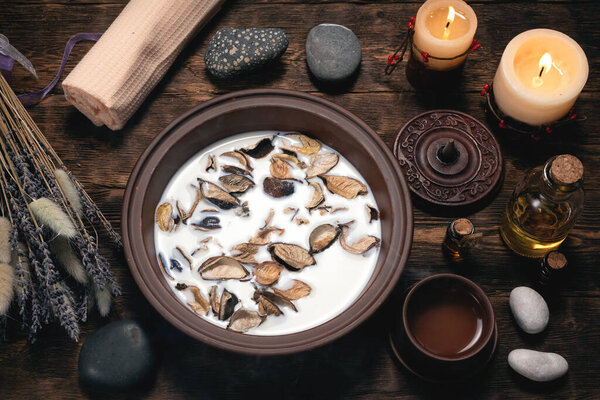 Aromatherapy concept background. Milk in a bowl with incense and essential oil on a brown wooden table background.