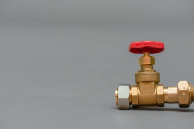 Su borusundaki kırmızı vana. Gri arkaplandaki fotokopi boşluğuna yakın..