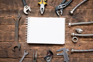 Fotokopi alanı olan düz arkaplan döşeme. İş aletleri, boru hattı ekipmanları ve tesisatçı tezgahında boş bir sayfa defteri. Liste modellemesini düzelt.