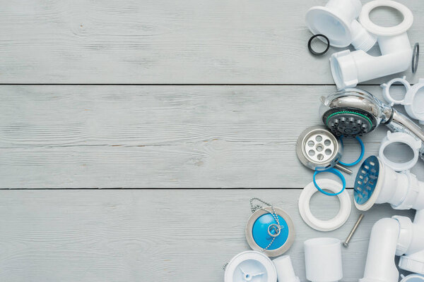 Shower plastic siphon parts on white wooden floor background.
