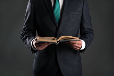 İşadamı elinde gri bir arka plan üzerine bir kitap okuyor. İş eğitimi. Hesap Defteri.