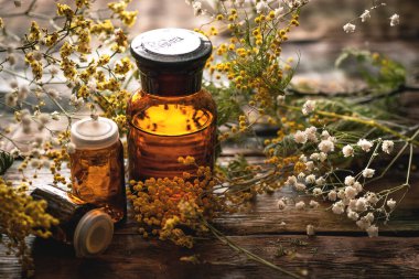 Wild flower essential oil bottle on a wooden board background. Herbal medicine. clipart