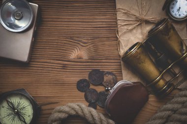 Seyahat ya da macera düz arka plan fotokopi alanı ile yatıyordu. Macera masası. Dürbün, bozuk para, el feneri, parşömen, demirleme halatı, pusula ve cep saati olan cüzdan..