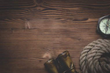 Seyahat ya da macera düz arkaplan bir kopya alanı ile yatıyordu. Dürbün, demirleme halatı ve ahşap bir masanın üzerindeki pusula..