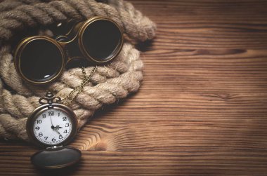 Fotokopi alanı olan seyahat ya da macera arka planı. Dürbünler, cep saati ve kahverengi ahşap bir masada demirleme halatı..