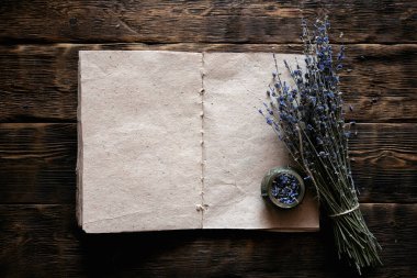 Kurutulmuş lavanta çiçeği dalı ve boş bir aromaterapi tarifi kitabı ahşap masa zemininde fotokopi alanı ile taklit ediliyor. Bitkisel tıp konsepti.