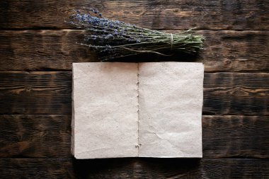 Kurutulmuş lavanta çiçeği dalı ve boş bir aromaterapi tarifi kitabı ahşap masa zemininde fotokopi alanı ile taklit ediliyor. Bitkisel tıp konsepti.