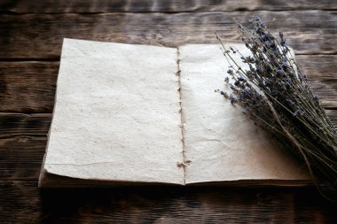 Kurutulmuş lavanta çiçeği dalı ve boş bir aromaterapi tarifi kitabı ahşap masa zemininde fotokopi alanı ile taklit ediliyor. Bitkisel tıp konsepti.