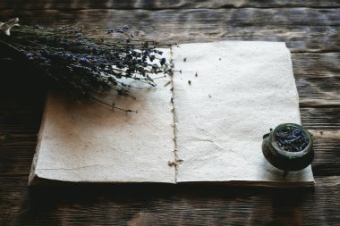 Kurutulmuş lavanta çiçeği dalı ve boş bir aromaterapi tarifi kitabı ahşap masa zemininde fotokopi alanı ile taklit ediliyor. Bitkisel tıp konsepti.