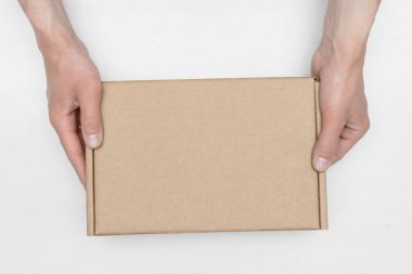 Bir karton kutu içinde teslimatçı beyaz ahşap masa arkaplanına uzanır. Teslimat hizmeti kavramı.