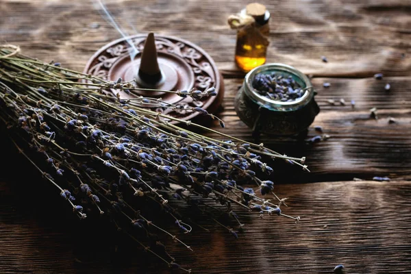 Dried lavender flower branches and lavender essential oil bottles on a wooden table background. Herbal medicine or aromatherapy concept.