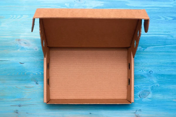青い木製のテーブルの背景に小包段ボール箱を開きます 配送サービスのコンセプト — ストック写真
