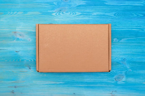 青い木製のテーブルの背景に閉じた小包段ボール箱 配送サービスのコンセプト — ストック写真