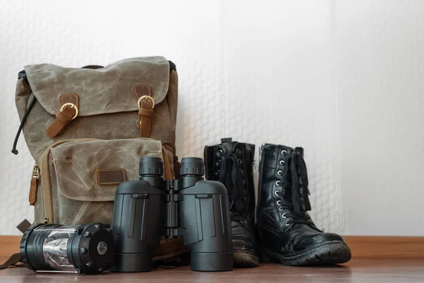 Uma Mochila Binóculos Lanterna Botas Pretas Soalho Fundo Parede Branco — Fotografia de Stock