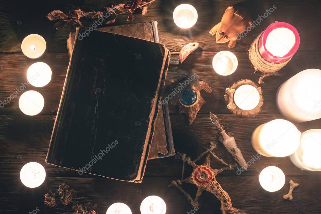 Magic book on the table in the light of burning candles. Witchcraft concept.