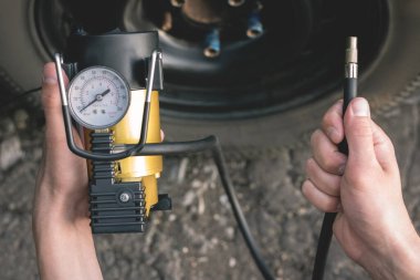 Şoför arabanın tekerleğini pompalıyor..