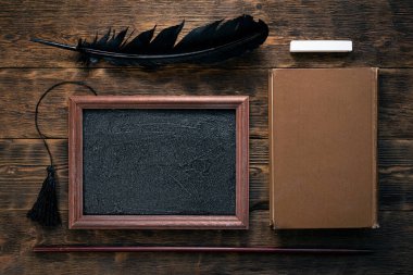 Tahta çerçeve, ders kitabı, okul işaretçisi ve kahverengi ahşap arka planda bir parça tebeşir. Eğitim kavramı.