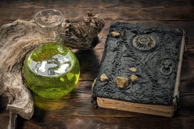 Sihirli kitap ve sihirli iksir şişesi kahverengi tahta masa arkasında. Büyücülük. Cadı doktor..