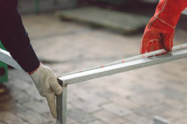 İşçiler demir çerçevenin uzunluğunu mezurayla ölçüyorlar.