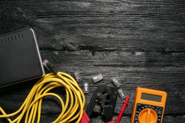 Bilgisayar ağı kurma kavramı. Crimper aracı, utp kablo, ağ anahtarı ve siyah ahşap masa üzerindeki konnektörler kopya alanı ile düz yatıyordu.