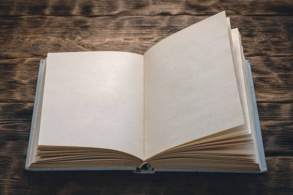 Blank page open book with copy space on brown wooden desk background.