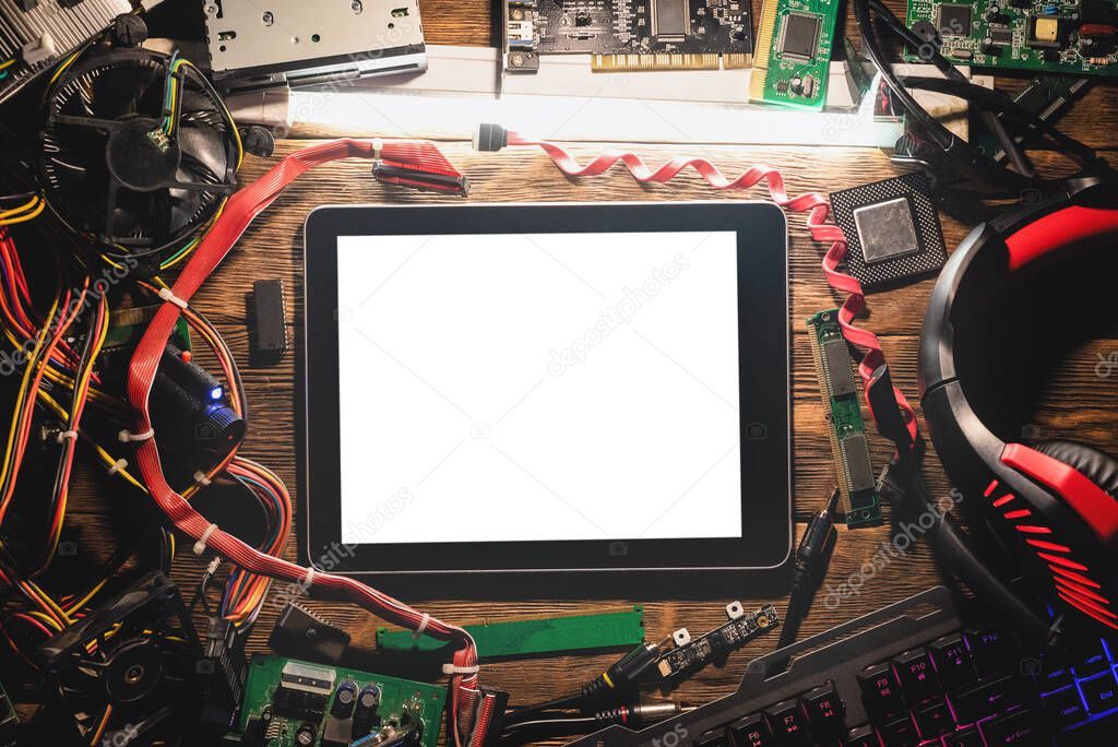 A blank screen digital tablet computer and old computer parts on the wooden flat lay table background.