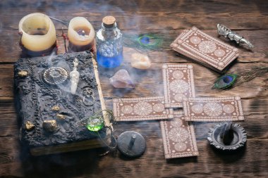 Tarot kartları, büyü kitabı ve ahşap masa arkasında zodyak tekerleği..