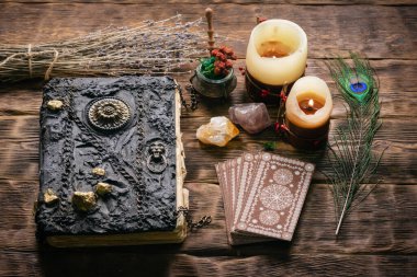 Tarot kartları, büyü kitabı ve ahşap masa arkasında zodyak tekerleği..