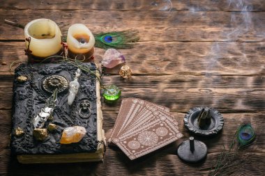 Tarot kartları, büyü kitabı ve ahşap masa arkasında zodyak tekerleği..