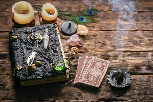 Tarot cards, book of magic and zodiac wheel on the wooden table background.