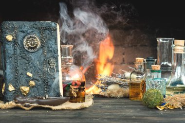 Sihirli iksir ve büyü kitabı şömine arkasında yanan ateşin olduğu masanın üstünde. Büyücülük..