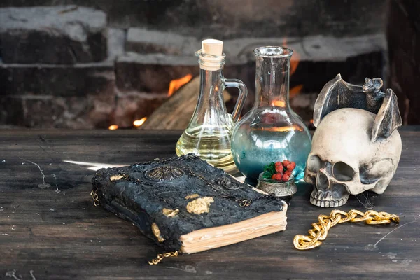 Magic potion and spell book on the table on burning fire in fireplace background. The Witchcraft.