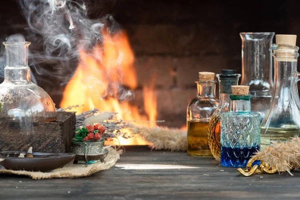 Magic potion on the table on burning fire in fireplace background. Alchemy concept.