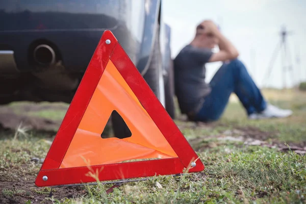 Bozuk arabanın arka planında uyarı üçgeni.